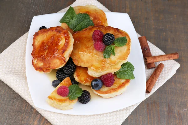 新鮮なベリーとおいしいパンケーキ、プレート、木製の背景上に蜂蜜とミントの葉 — ストック写真