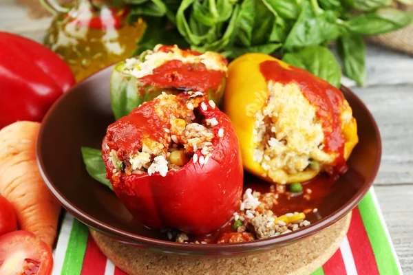 Composición con pimientos rellenos preparados en plato y hierbas frescas, especias y verduras, sobre fondo de madera — Foto de Stock