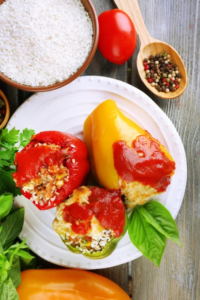 Composition with prepared stuffed peppers on plate and fresh herbs, spices and vegetables, on wooden background — Stock Photo, Image