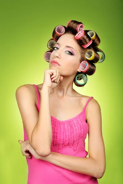 Menina bonita em encrespadores de cabelo no fundo verde — Fotografia de Stock