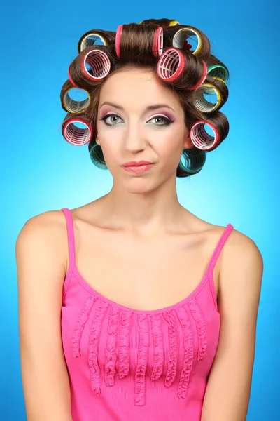 Beautiful girl in hair curlers on blue background — Stock Photo, Image