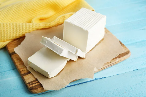 Frische Butter auf Schneidebrett, auf farbigem Holzgrund — Stockfoto