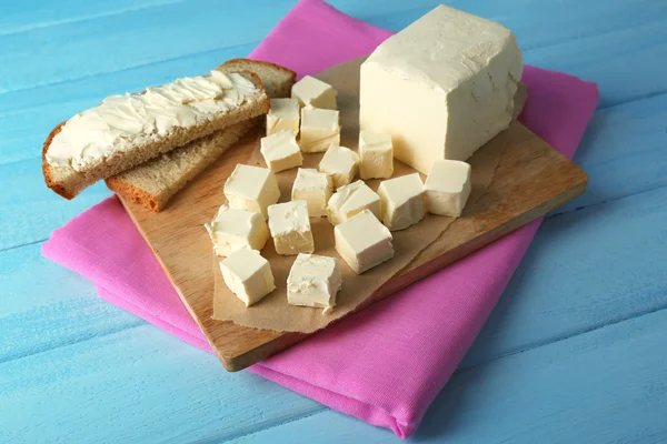 Fresh butter on cutting board and homemade bread, on color wooden background — Stock Photo, Image