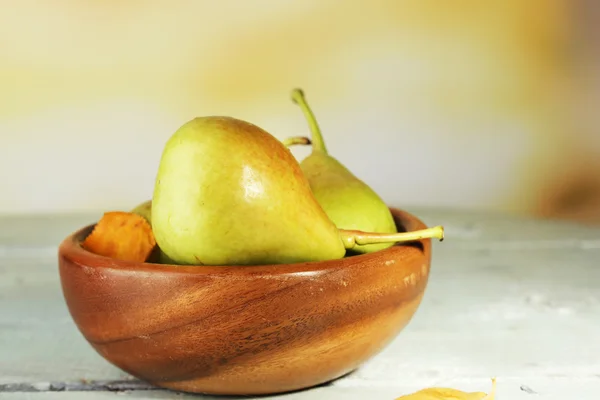 Poires mûres savoureuses dans un bol en bois, sur la table, sur fond de nature — Photo