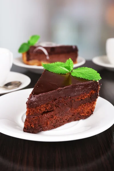 Stukken van chocolade taart op platen en kopje thee op houten tafel op natuurlijke achtergrond — Stockfoto