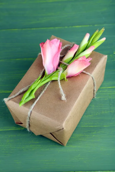 Přírodní styl ručně vyráběné dárkové krabice s čerstvými květinami a rustikální provázkem, na dřevěné pozadí — Stock fotografie