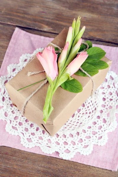 Scatola regalo artigianale in stile naturale con fiori freschi e spago rustico, su sfondo in legno — Foto Stock