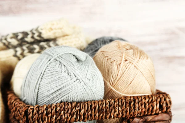 Knitting yarn and socks in basket, on wooden background — Stock Photo, Image