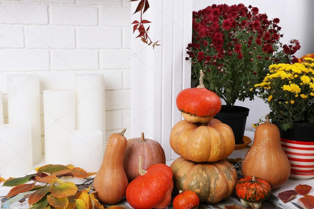 Pumpkins and flowers on brick wall and candles background