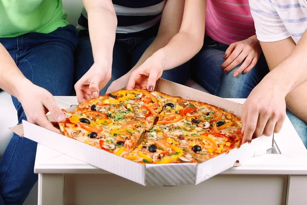 Grupa młodych przyjaciół jeść pizzę w salonie na kanapie — Zdjęcie stockowe