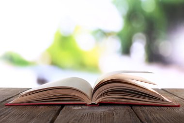 Doğal arka planda tahta masa üzerine açık bir kitap