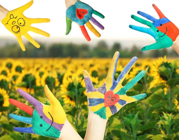 Gemalte Hände auf Sonnenblumenfeld Hintergrund — Stockfoto