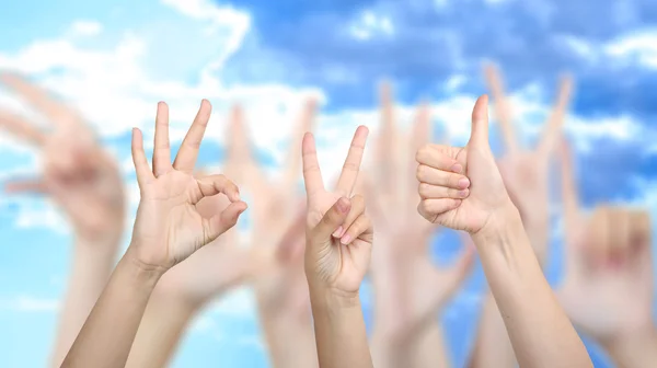 La gente muestra diferentes manos signos en el fondo del cielo — Foto de Stock