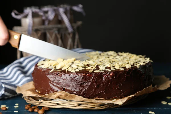 Torta de chocolate de corte femenino con almendra, sobre mesa de madera, sobre fondo oscuro —  Fotos de Stock