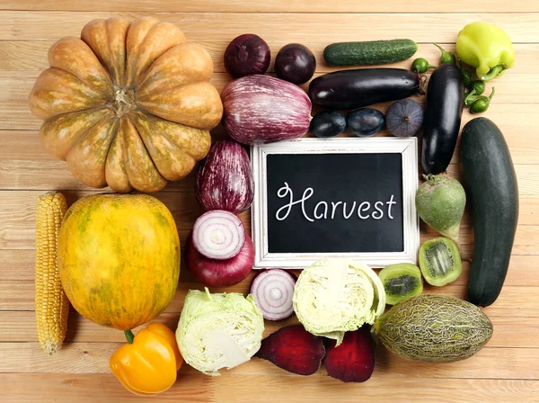 Fresh organic vegetables with chalkboard on wooden table, close up — Stock Photo, Image