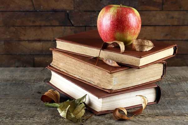 Apfel mit Büchern und trockenen Blättern — Stockfoto