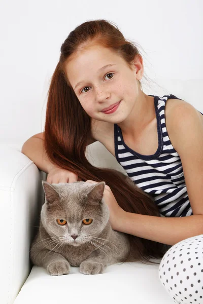 Hermosa niña con gato en el sofá en la habitación — Foto de Stock