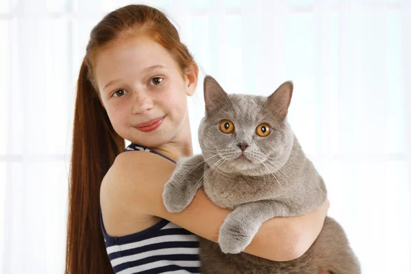 Güzel küçük bir kız ile ışık arka plan üzerinde kedi — Stok fotoğraf