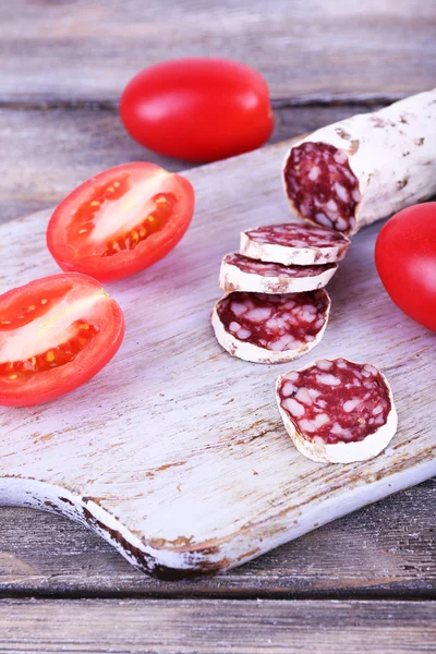 Salami francés con tomates sobre tabla de cortar sobre fondo de madera —  Fotos de Stock