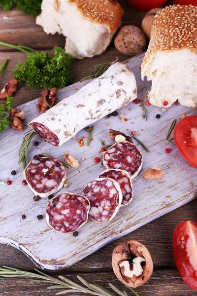 French salami with tomatoes, parsley and bread on cutting board on wooden background — Stock Photo, Image