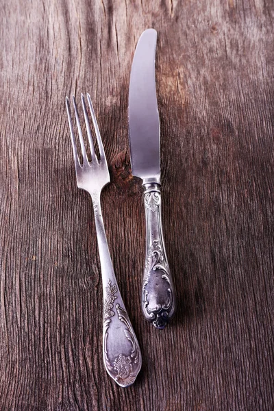 Cuchillo y tenedor de metal sobre fondo de madera — Foto de Stock