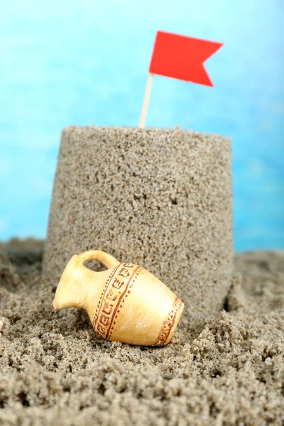 Sandcastle with flag on sandy beach — Stock Photo, Image