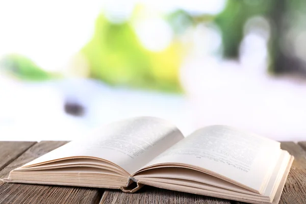 Open book on wooden table on natural background — Stock Photo, Image