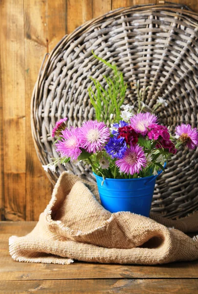 Flores silvestres brillantes en cubo sobre fondo de madera — Foto de Stock