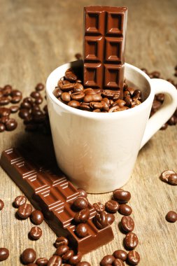 Fincan kahve çekirdekleri ve ahşap zemin üzerine koyu çikolata sır