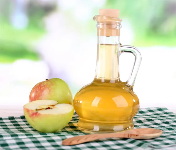 Cuka sari apel dalam botol kaca dan apel matang segar, di atas meja kayu, di latar belakang alam — Stok Foto