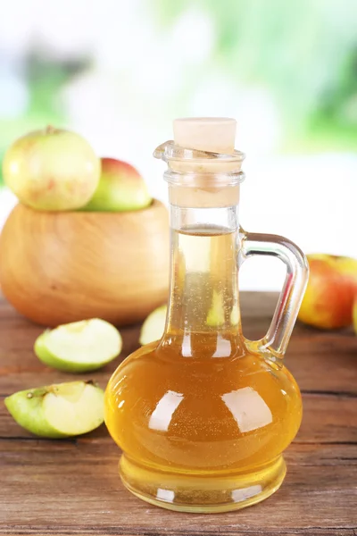 Vinagre de sidra de manzana en botella de vidrio y manzanas frescas maduras, sobre mesa de madera, sobre fondo natural —  Fotos de Stock