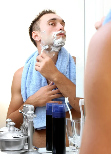 Jeune homme rasant sa barbe dans la salle de bain — Photo