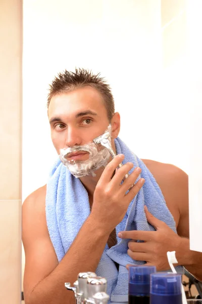 Jeune homme rasant sa barbe dans la salle de bain — Photo