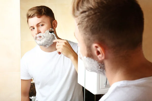 Jovem barbear sua barba no banheiro — Fotografia de Stock