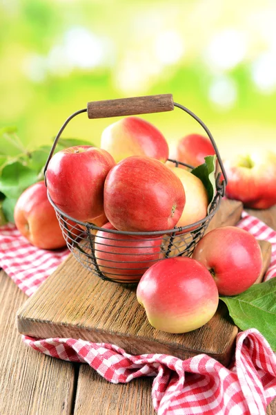 Manzanas dulces en canasta de mimbre sobre mesa sobre fondo brillante — Foto de Stock