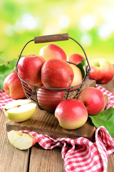 Manzanas dulces en canasta de mimbre sobre mesa sobre fondo brillante — Foto de Stock