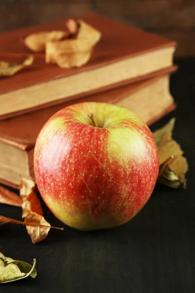 Äpple med böcker och torra löv — Stockfoto
