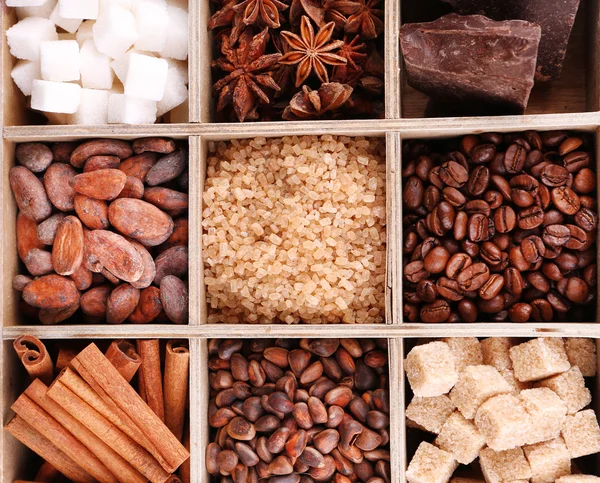 Wooden box with set of coffee and cocoa beans, sugar cubes, dark chocolate, cinnamon and anise over wooden background — Stock Photo, Image