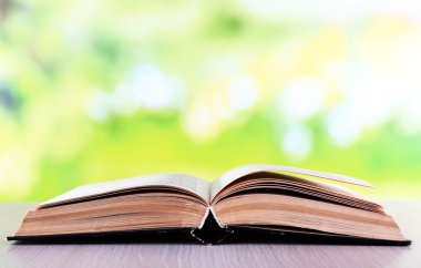 Doğal arka planda tahta masa üzerine açık bir kitap