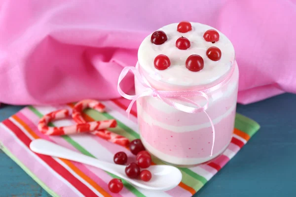 Raspberry milk dessert in glass jar, on color wooden background — Stock Photo, Image