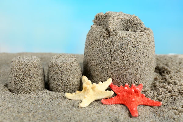 Sandcastle with starfish on sandy beach — Stock Photo, Image