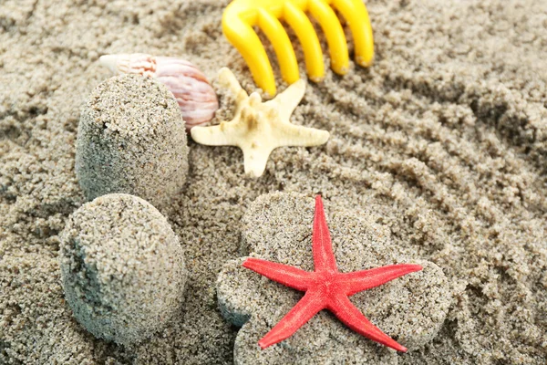 Blumen- und burgenförmiger Sand, Seesterne und Kinderspielzeug aus nächster Nähe — Stockfoto