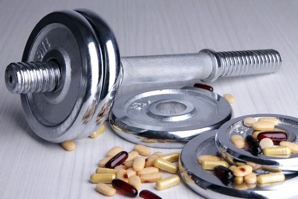 Dumbbell and colorful pills — Stock Photo, Image