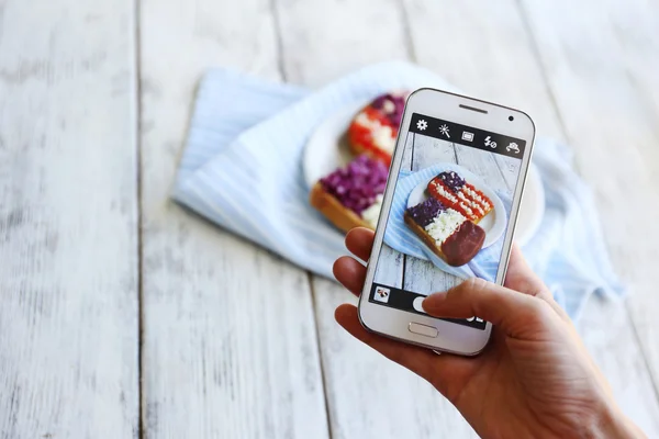 Hand att göra foto av smörgåsar med flaggor på mobiltelefon för sociala nätverk — Stockfoto