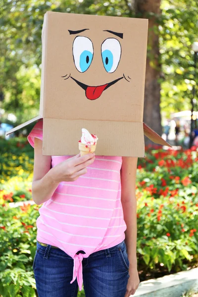 Donna con scatola di cartone in testa con felice viso che tiene il gelato, all'aperto — Foto Stock