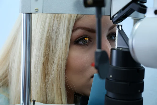 Concepto de optometría: mujer joven y bonita que tiene los ojos examinados por un oftalmólogo — Foto de Stock