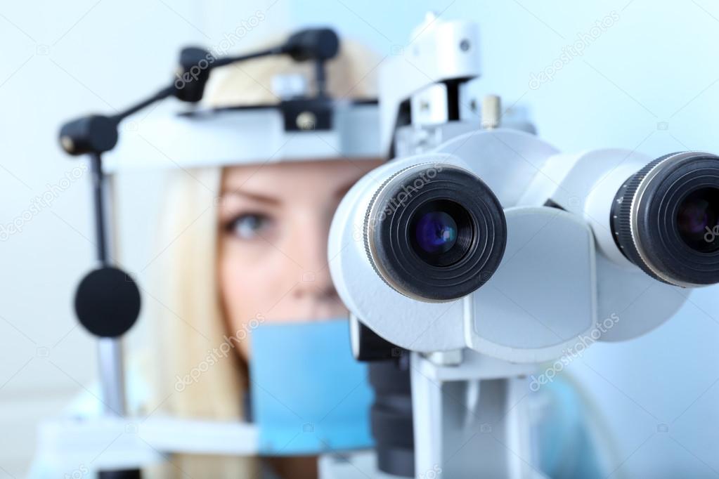 Optometry concept pretty young woman having her eyes examined by eye doctor Stock Photo by