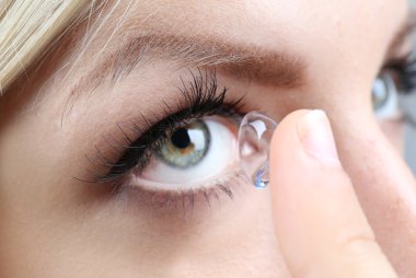 Medicine and vision concept - young woman with contact lens, close up clipart