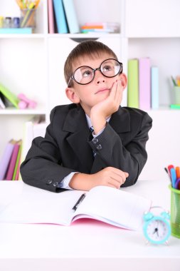 школяр, сидячи на столі в класі