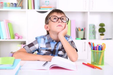 школяр, сидячи на столі в класі